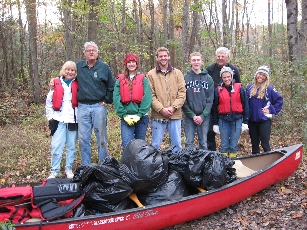 Volunteers with pile of trash bags in a canoe at Blackstone Canal